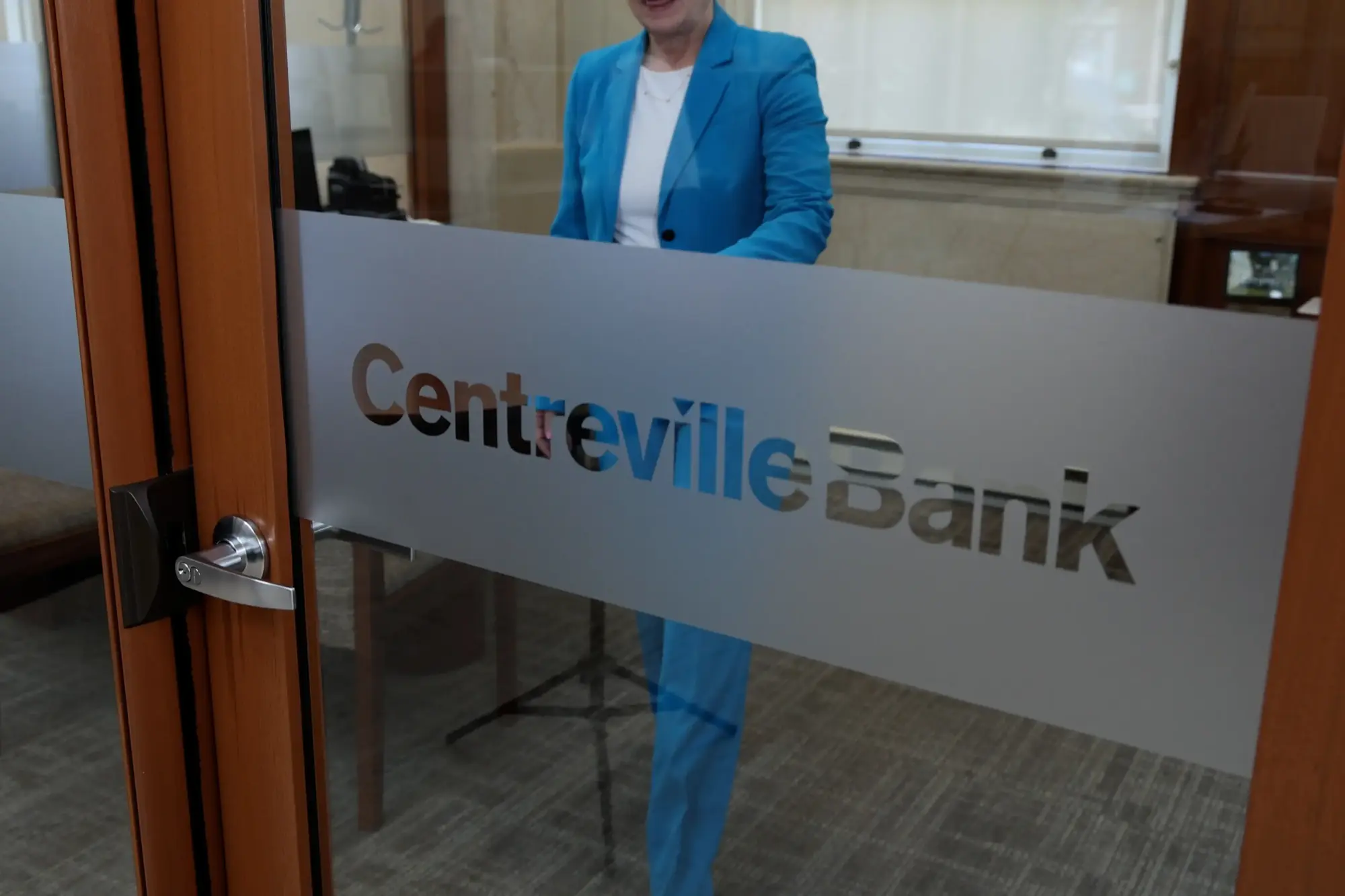 Professional woman in blue blazer standing behind Centreville Bank reception desk in modern office lobby