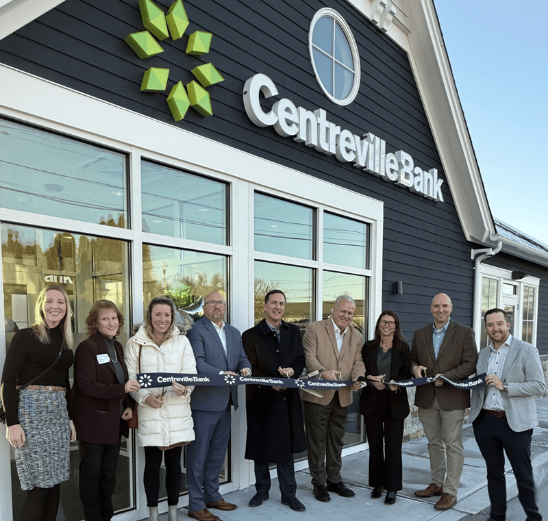 Group cutting a branded ribbon outside a Centreville Bank branch building.