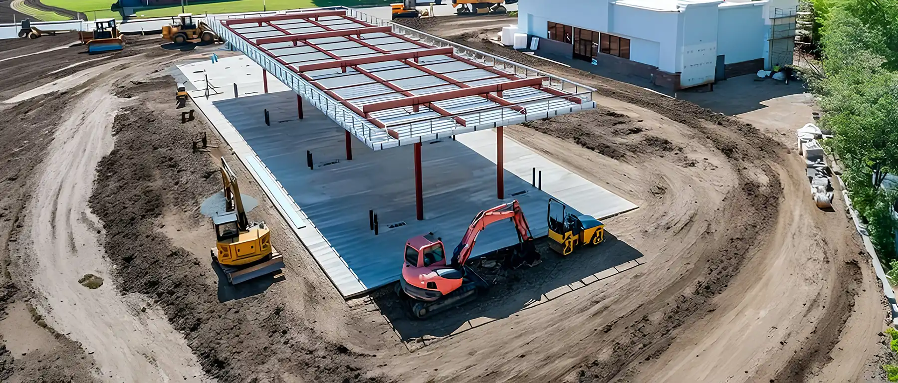 Aerial view of a commercial construction site with steel building framework and excavators