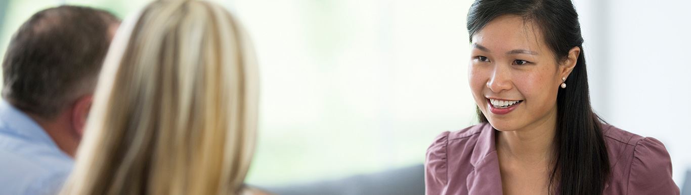 Professional woman in purple blazer smiling during business meeting with colleagues in office setting