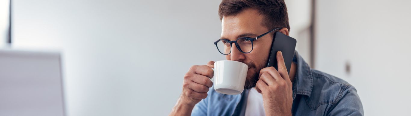 gentleman sipping coffee while on his cellphone