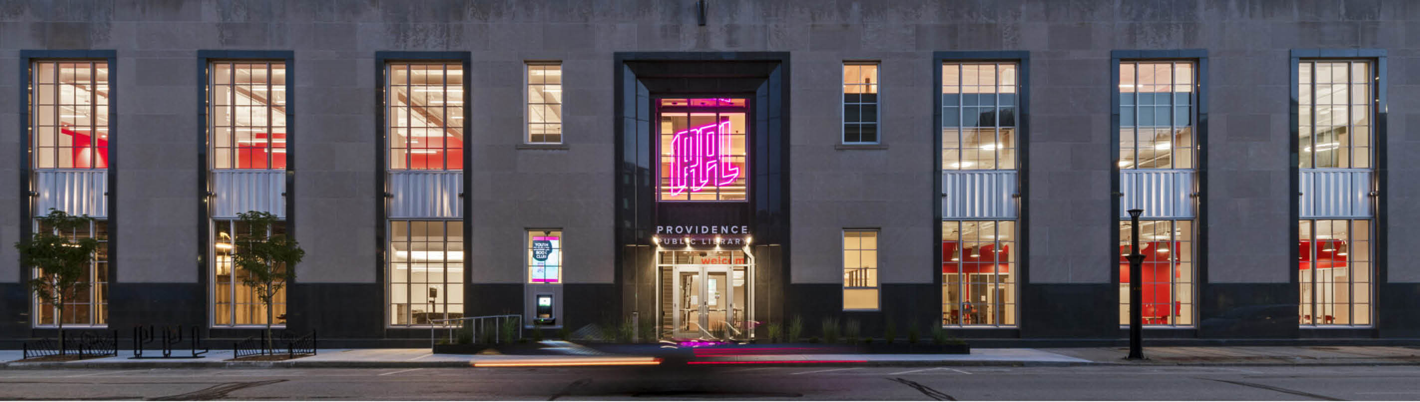 The Providence Public Library facade at dusk, a neon pink PPL sign glowing above the entrance