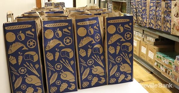 Rows of paper grocery bags printed with food illustrations, packed and lined up ready for collection