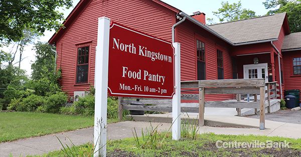 Sign outside the red clapboard North Kingstown Food Pantry reading Mon.-Fri. 10 am-2 pm