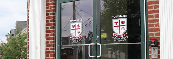 Glass entrance doors carrying the YouthBuild Preparatory Academy crest